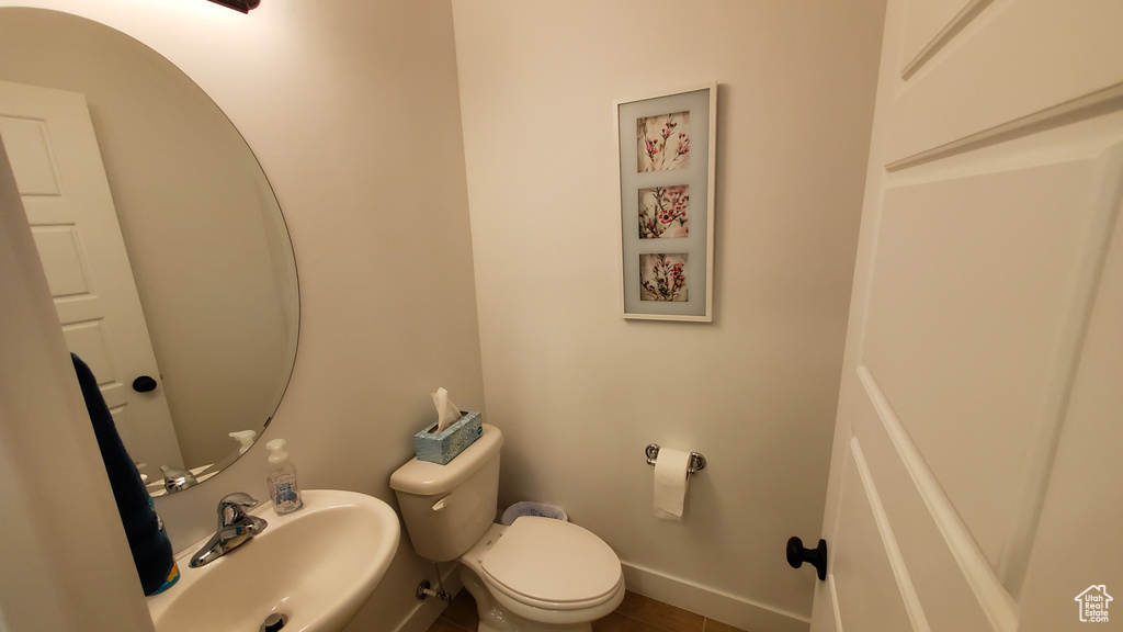 Bathroom featuring a sink, toilet, and baseboards