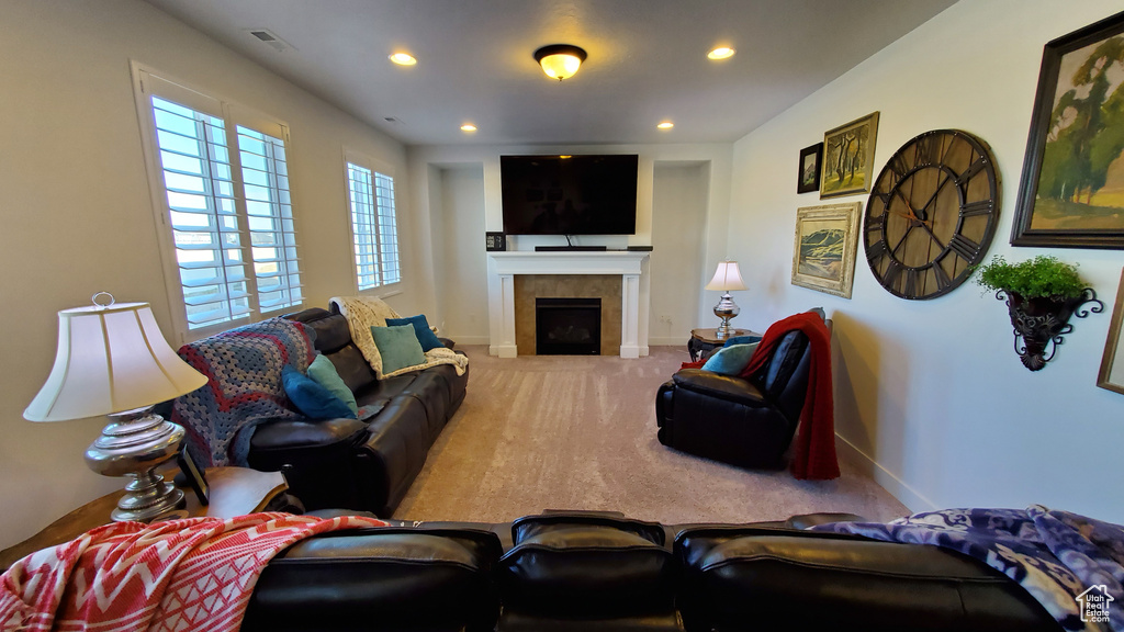 Carpeted living room featuring baseboards, a tiled fireplace, and recessed lighting