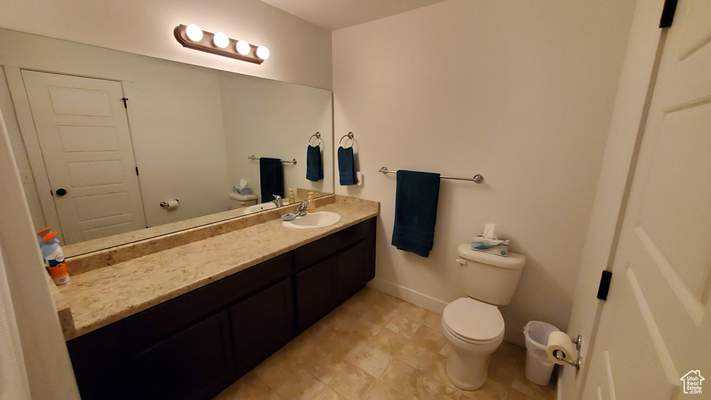 Bathroom featuring toilet, vanity, baseboards, and tile patterned flooring