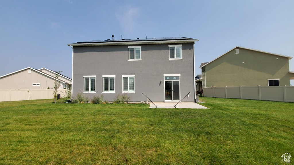 Back of property featuring solar panels, a patio area, and stucco siding