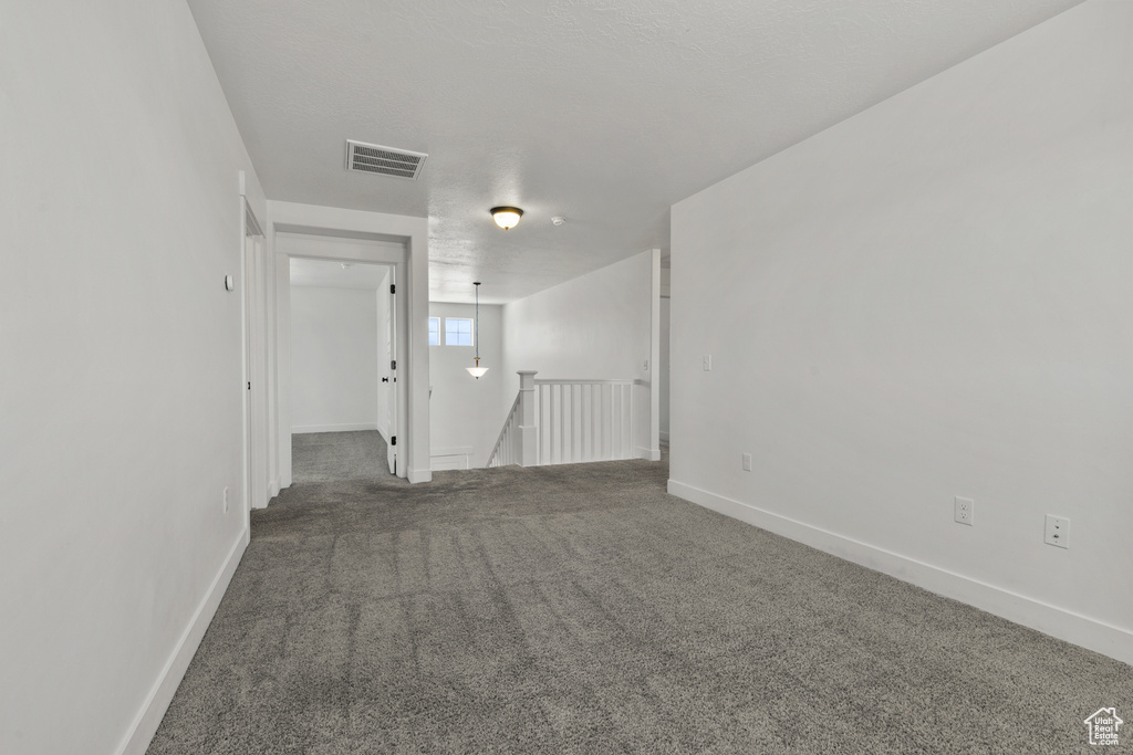Carpeted spare room featuring baseboards