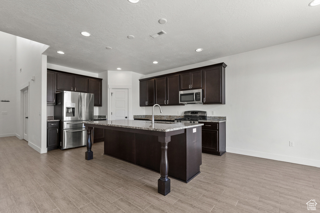 Kitchen featuring appliances with stainless steel finishes, baseboards, a sink, dark brown cabinetry, and recessed lighting