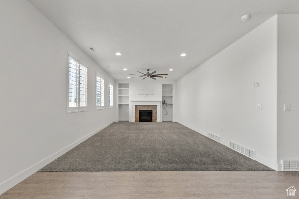 Unfurnished living room featuring a ceiling fan, baseboards, built in features, a fireplace, and recessed lighting