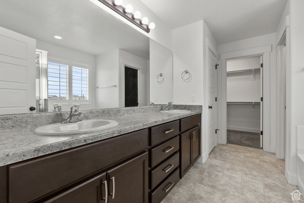 Bathroom with double vanity and a walk in closet