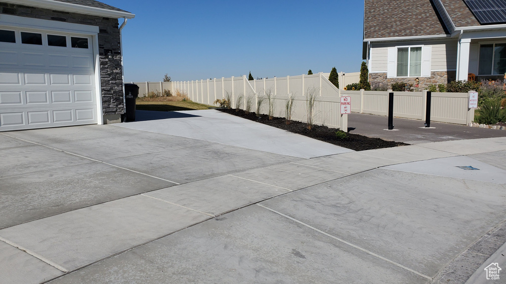Exterior space with concrete driveway, fence, and a garage