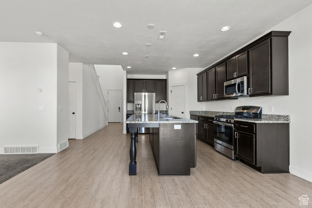 Kitchen with stainless steel appliances, recessed lighting, baseboards, light wood finished floors, and a kitchen breakfast bar