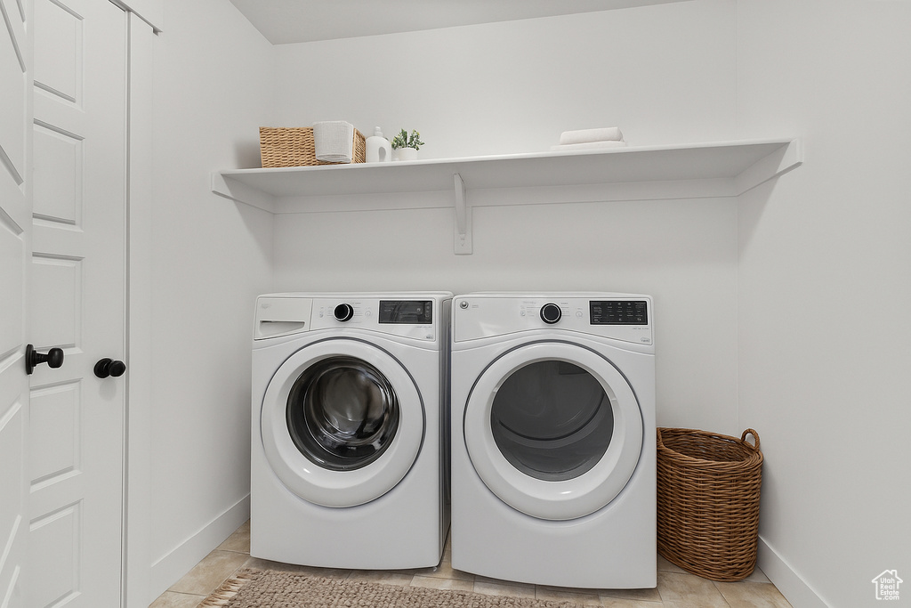Washroom with independent washer and dryer and light tile patterned floors