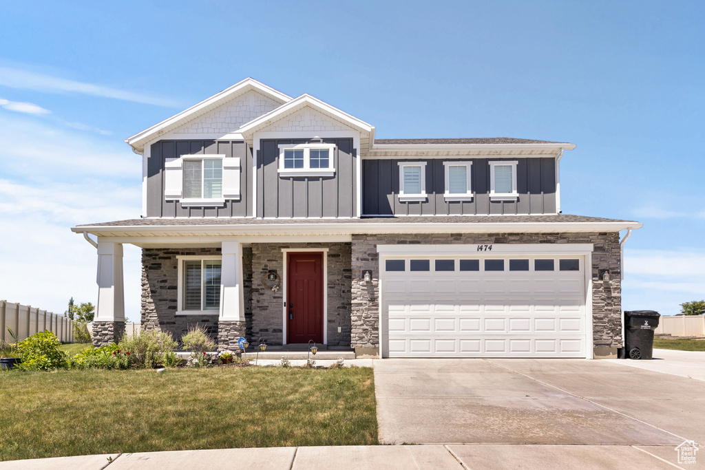 View of front of home featuring board and batten siding, driveway, a garage, and covered porch
