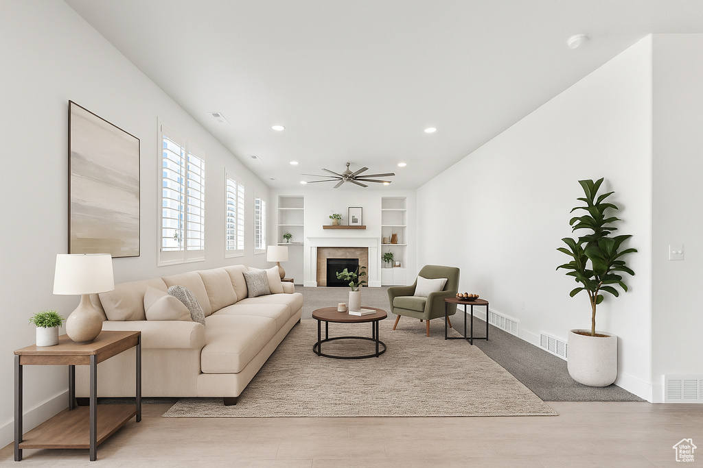 Living area featuring built in shelves, a ceiling fan, a tiled fireplace, recessed lighting, and wood finished floors