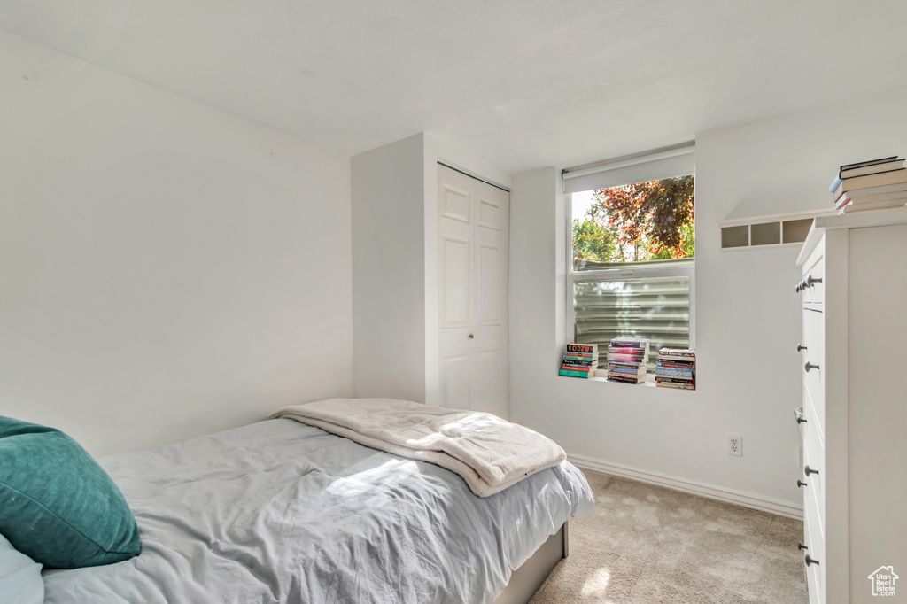 Bedroom featuring light carpet, a closet, and baseboards