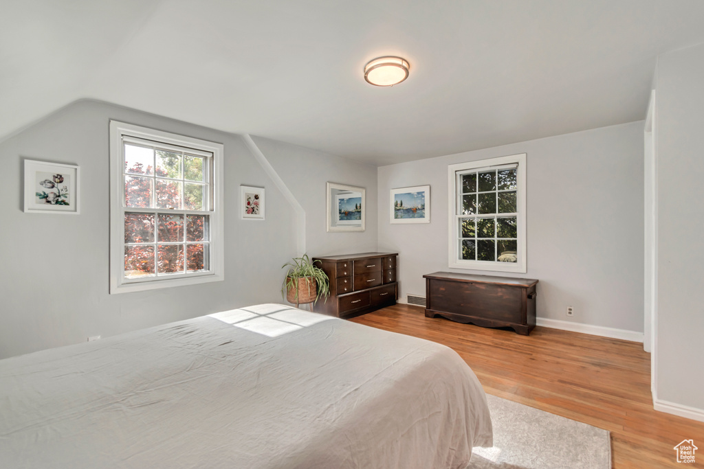 Bedroom with wood finished floors, lofted ceiling, and baseboards