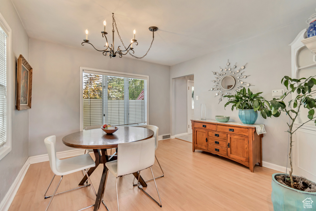 Dining space featuring light wood-type flooring, a chandelier, and baseboards