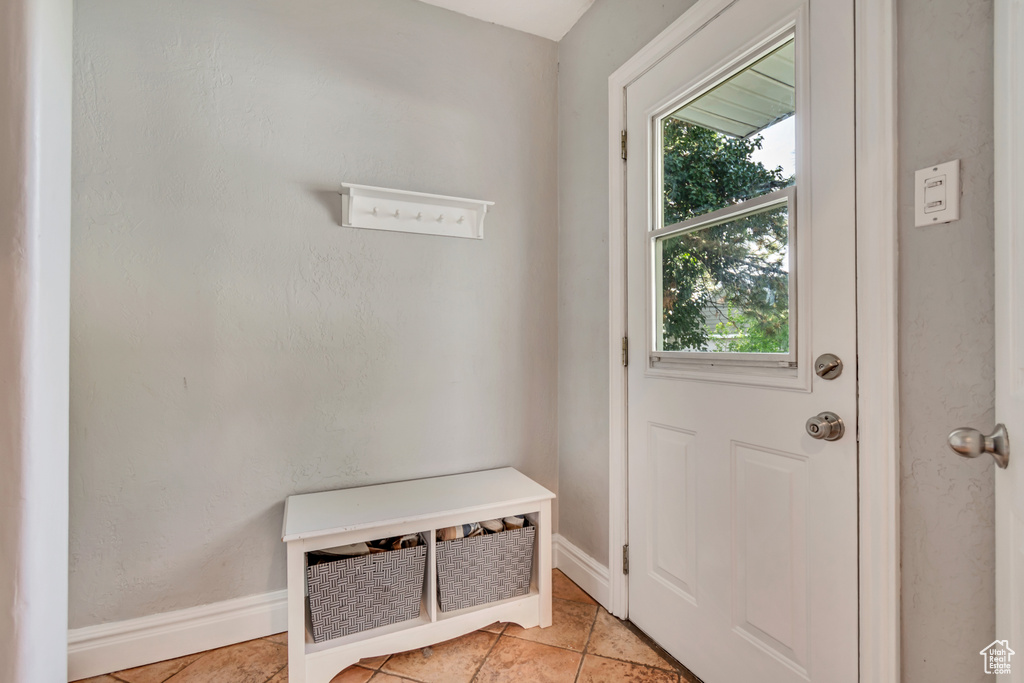 Doorway to outside with baseboards and light tile patterned flooring