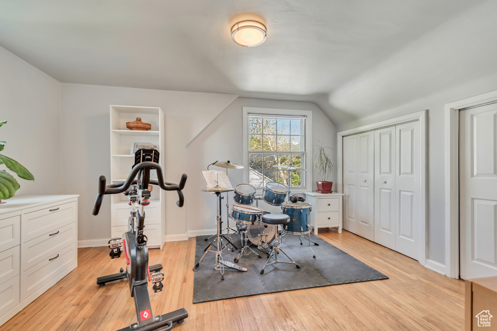 Workout area with light wood-style flooring, lofted ceiling, and baseboards