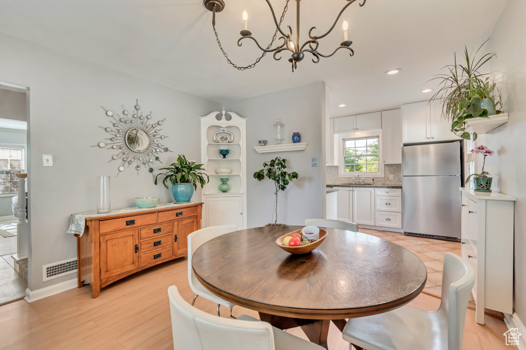 Dining room with a chandelier, light wood finished floors, recessed lighting, and baseboards
