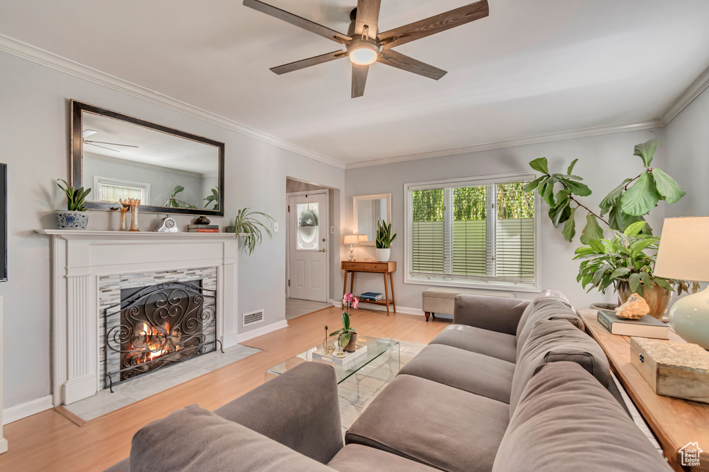 Living room featuring a ceiling fan, a high end fireplace, wood finished floors, ornamental molding, and baseboards