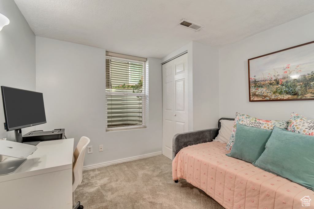 Bedroom with light colored carpet, a closet, baseboards, and an office area