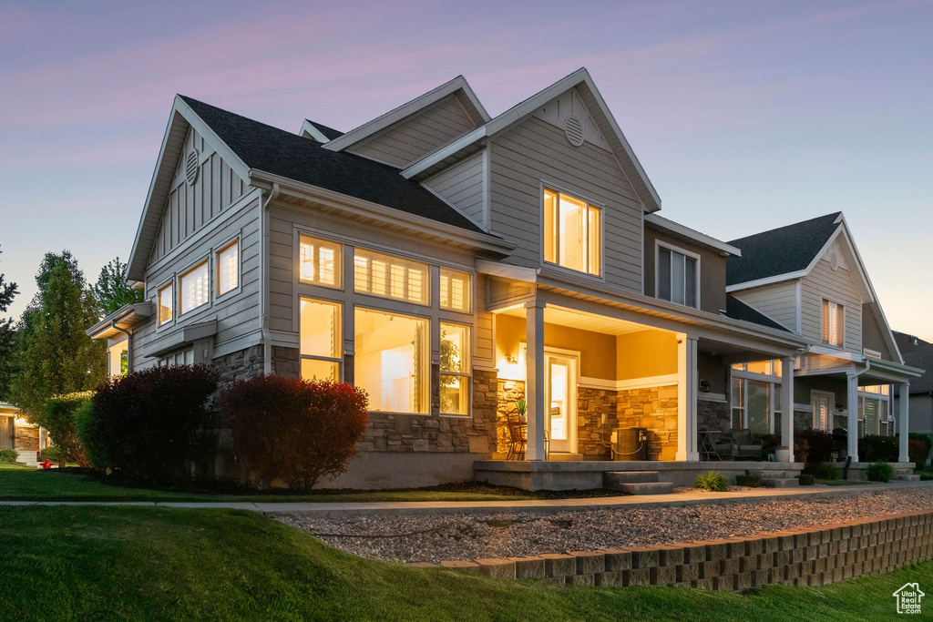 Back of house featuring stone siding, covered porch, and board and batten siding