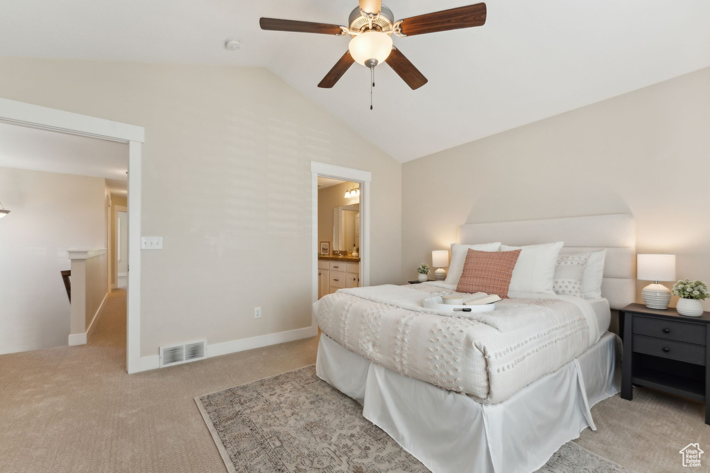 Bedroom with lofted ceiling, light carpet, a ceiling fan, ensuite bathroom, and baseboards