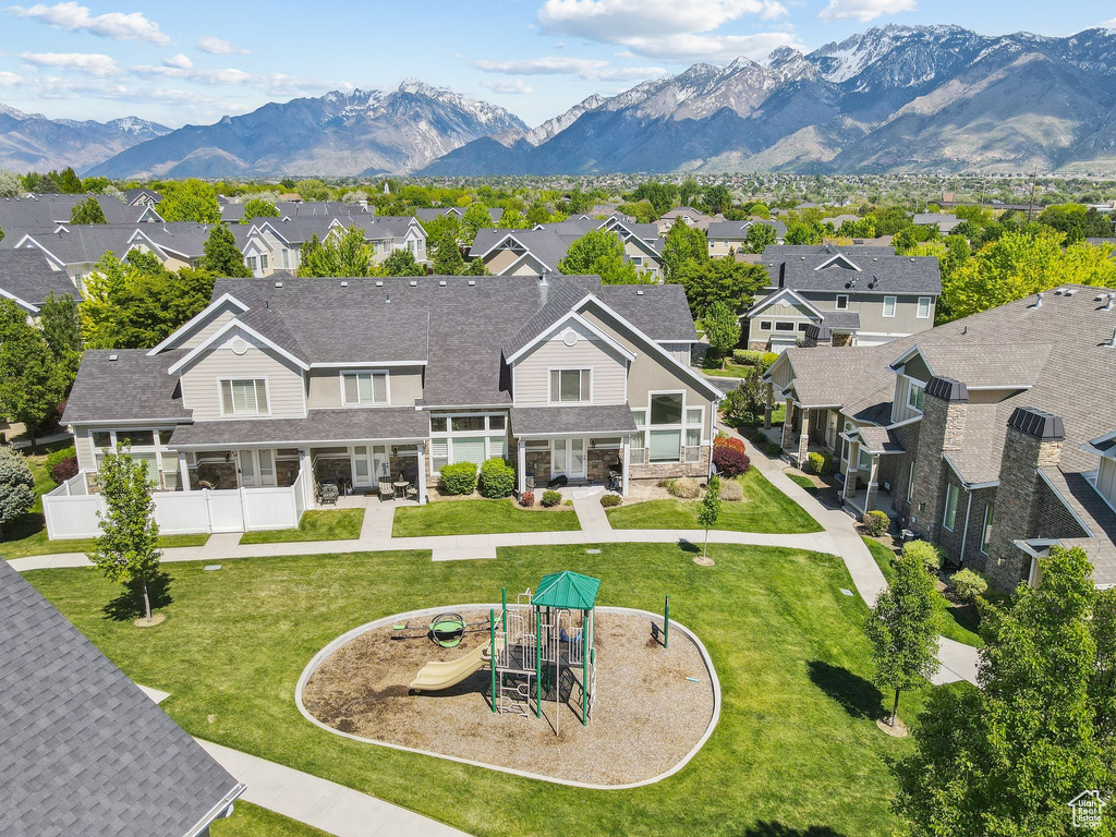 Back of property featuring a residential view, stone siding, a mountain view, and a lawn