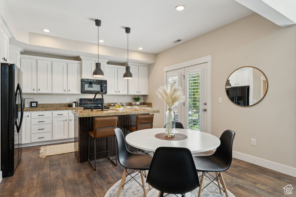 Kitchen featuring black appliances, dark wood finished floors, a center island with sink, white cabinetry, and recessed lighting