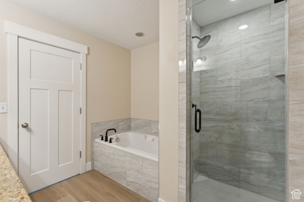 Bathroom featuring a shower stall, a garden tub, and wood finished floors