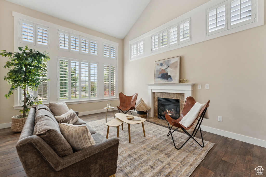 Living room with dark wood-type flooring, a high end fireplace, baseboards, and high vaulted ceiling