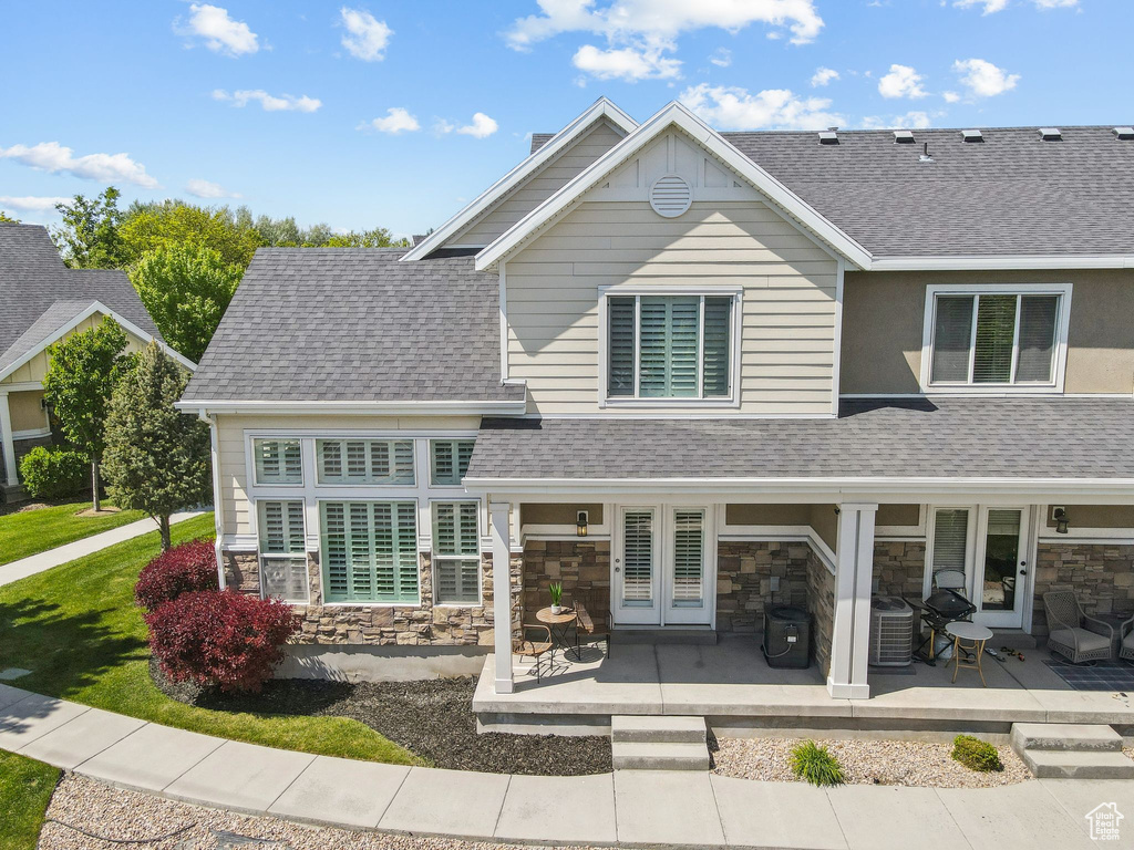 View of front of house featuring stone siding and roof with shingles