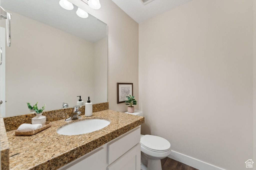 Bathroom with wood finished floors, vanity, toilet, and baseboards