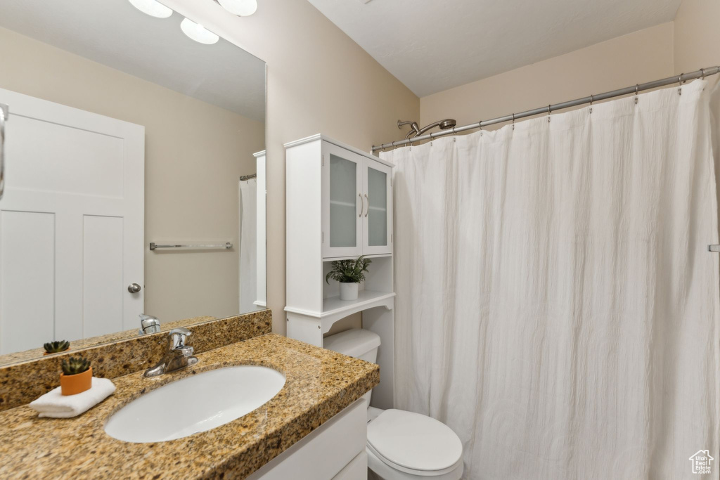 Bathroom with toilet, vanity, and curtained shower
