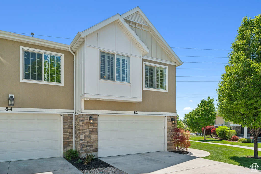 View of front facade with a garage, stone siding, board and batten siding, and concrete driveway