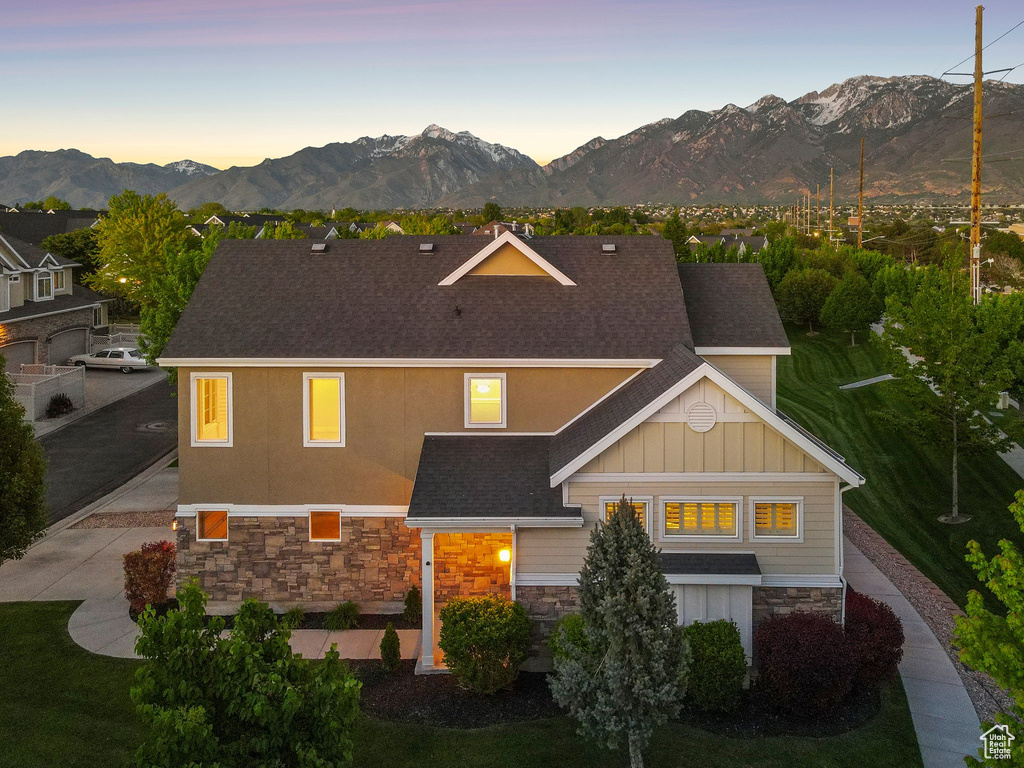 View of front facade featuring stone siding, a mountain view, roof with shingles, and board and batten siding