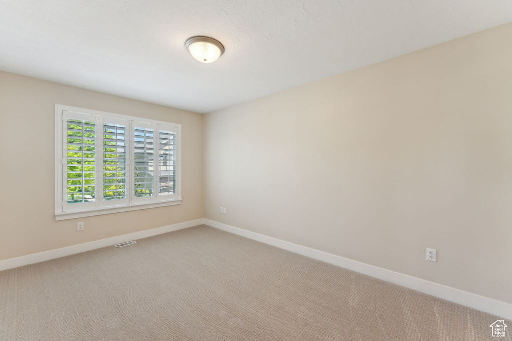Unfurnished room featuring baseboards and light carpet
