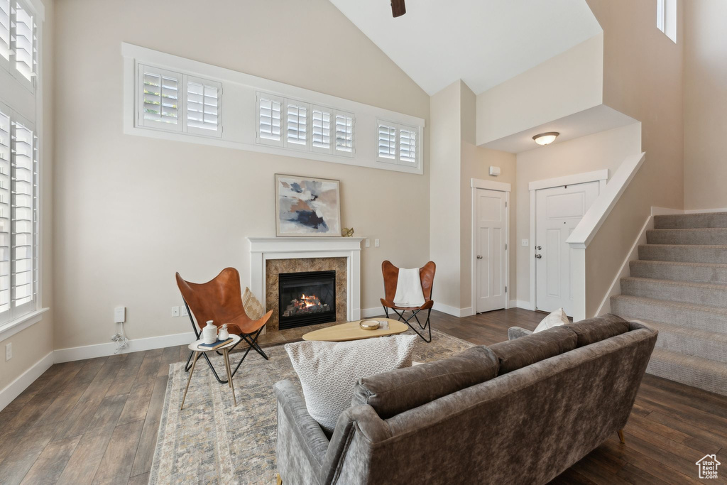 Living area featuring high vaulted ceiling, dark wood finished floors, a premium fireplace, stairway, and baseboards
