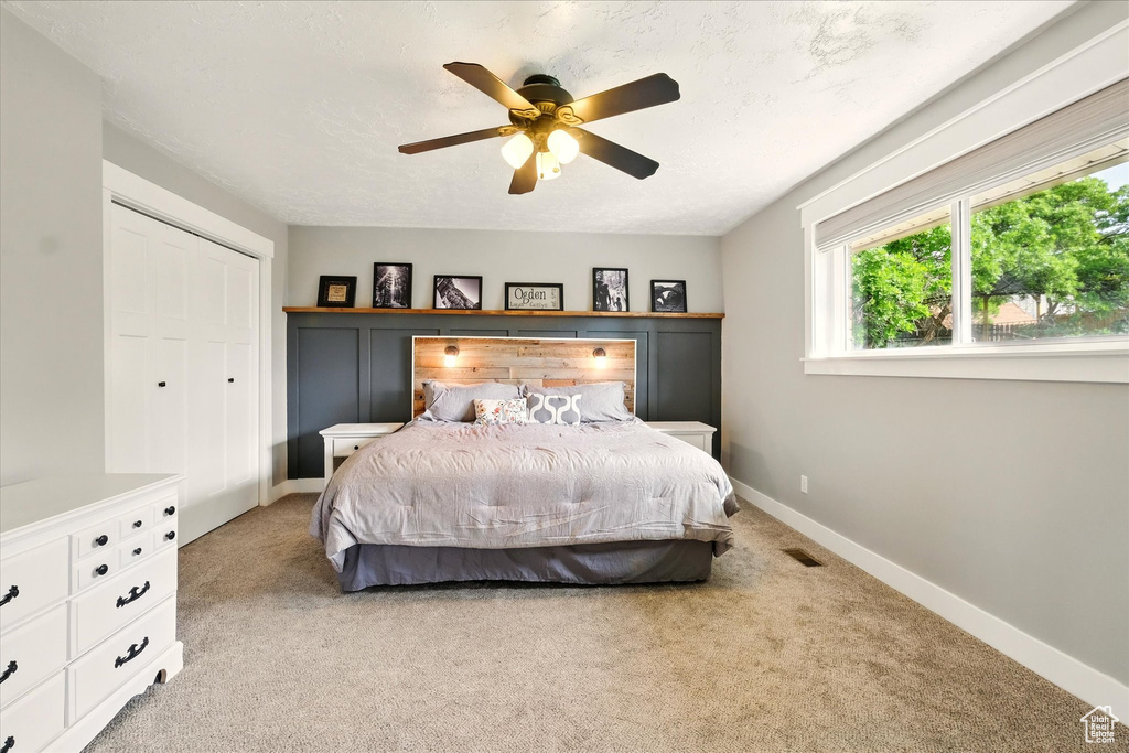 Bedroom with light carpet, baseboards, a ceiling fan, and a closet