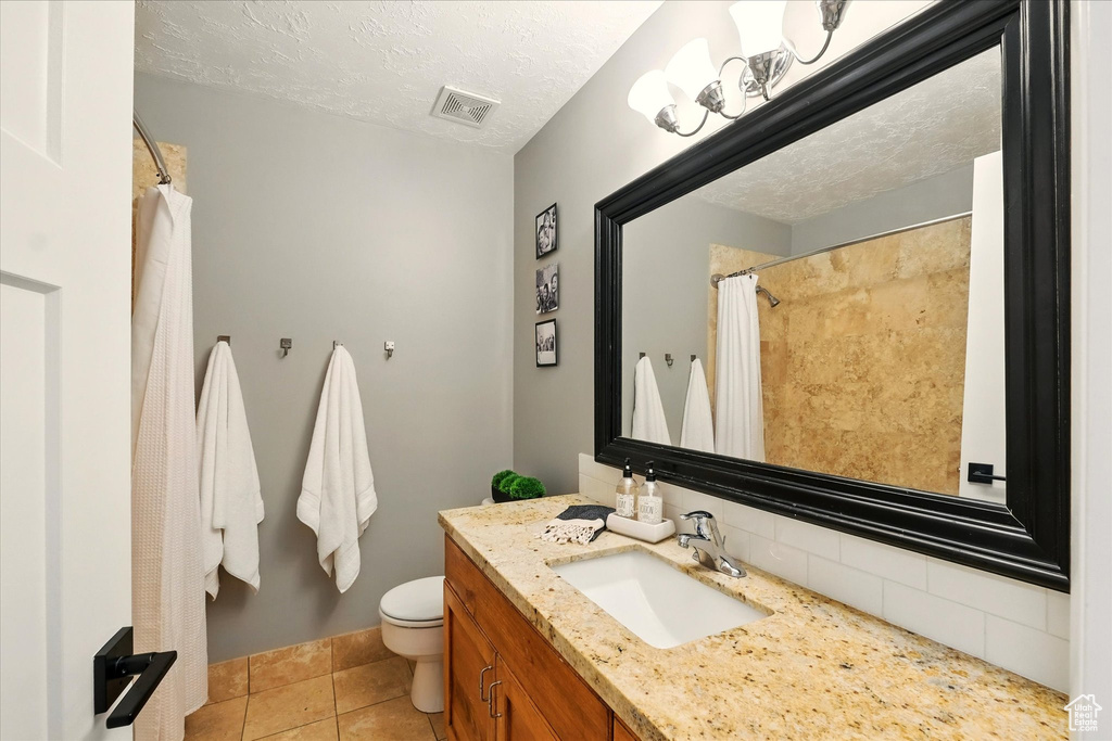 Bathroom featuring toilet, vanity, tile patterned flooring, backsplash, and a shower with curtain