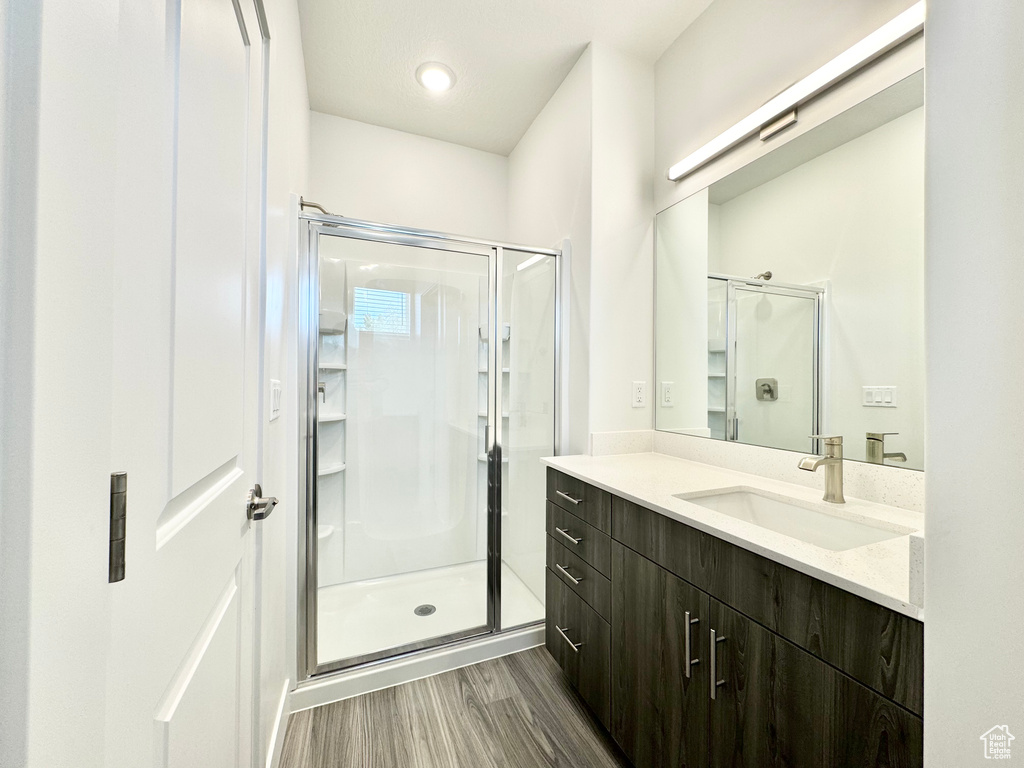Full bathroom with a stall shower, wood finished floors, and vanity