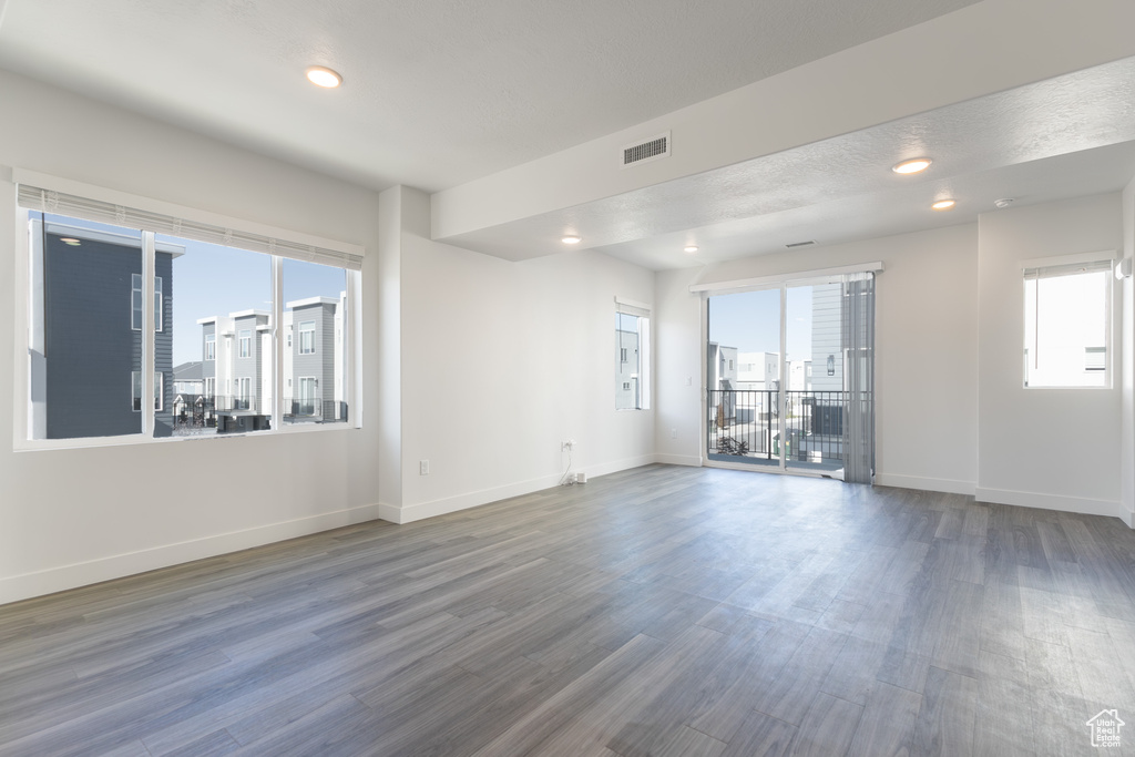 Spare room featuring healthy amount of natural light, wood finished floors, baseboards, and recessed lighting