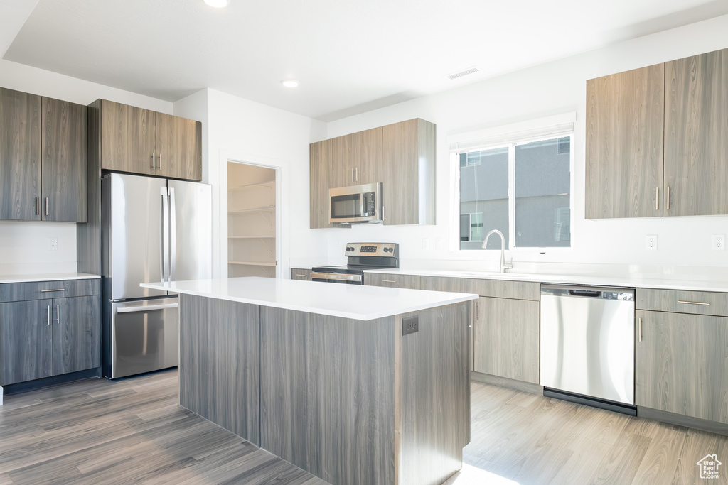 Kitchen with appliances with stainless steel finishes, modern cabinets, light wood-style flooring, light countertops, and recessed lighting