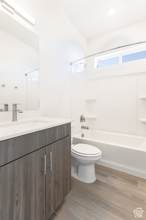 Bathroom featuring toilet, vanity, bathtub / shower combination, and wood finished floors
