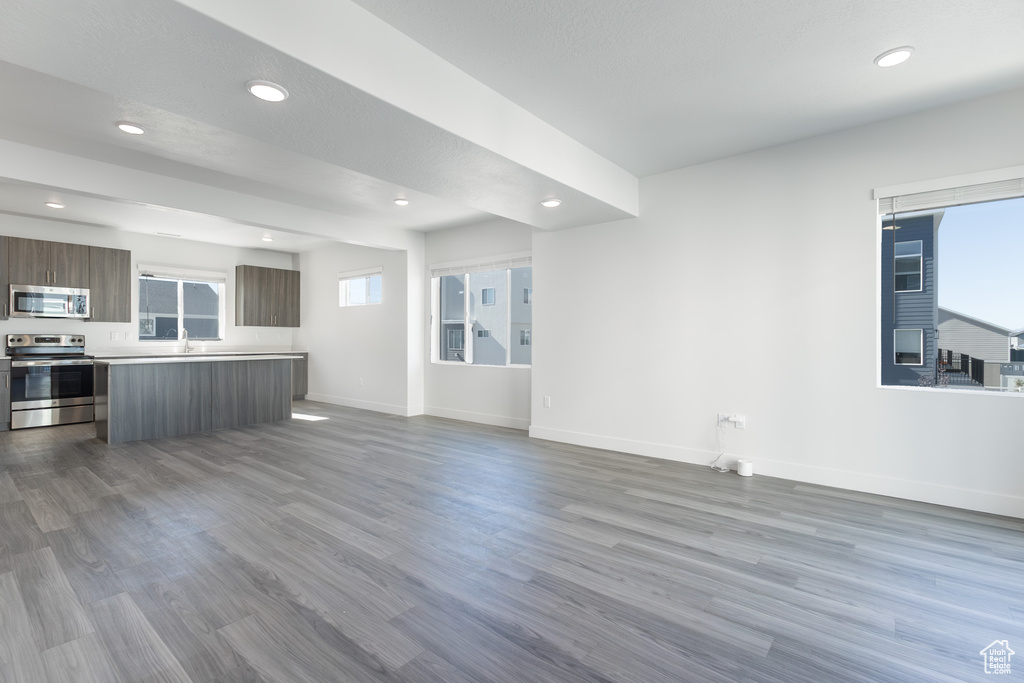 Unfurnished living room featuring baseboards, dark wood-type flooring, recessed lighting, and a sink