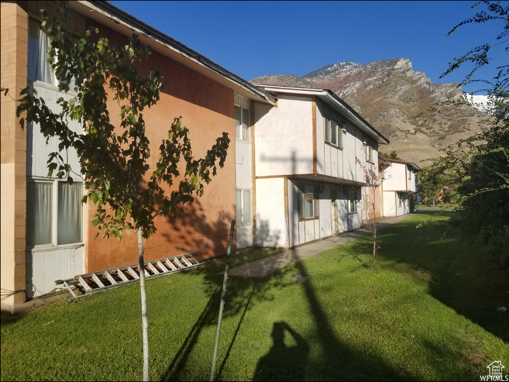 View of property exterior featuring a mountain view, a yard, and stucco siding