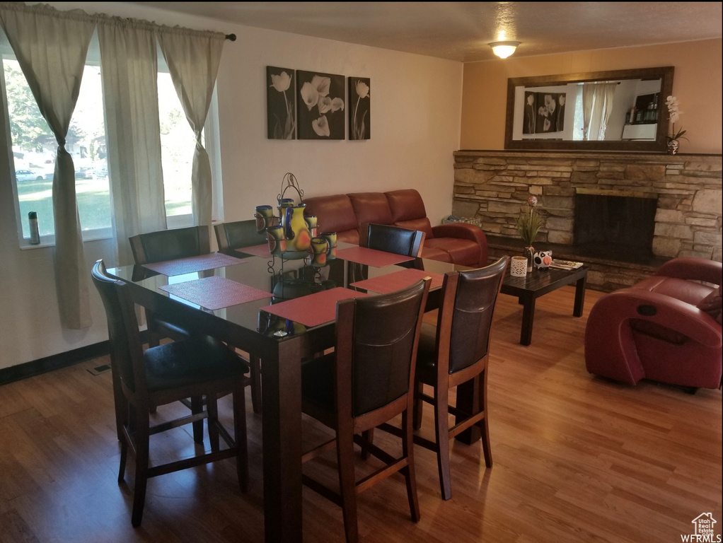 Dining space with wood finished floors and a stone fireplace