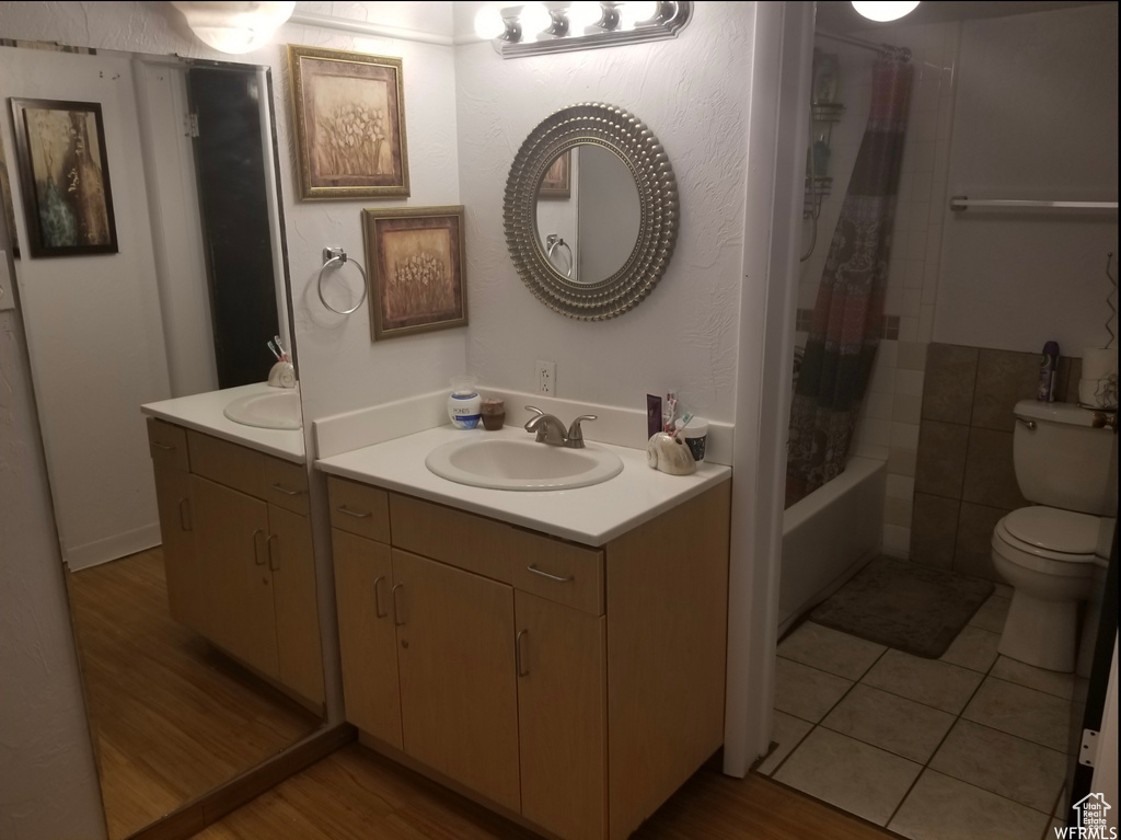 Bathroom featuring toilet, wood finished floors, vanity, and shower / tub combo with curtain