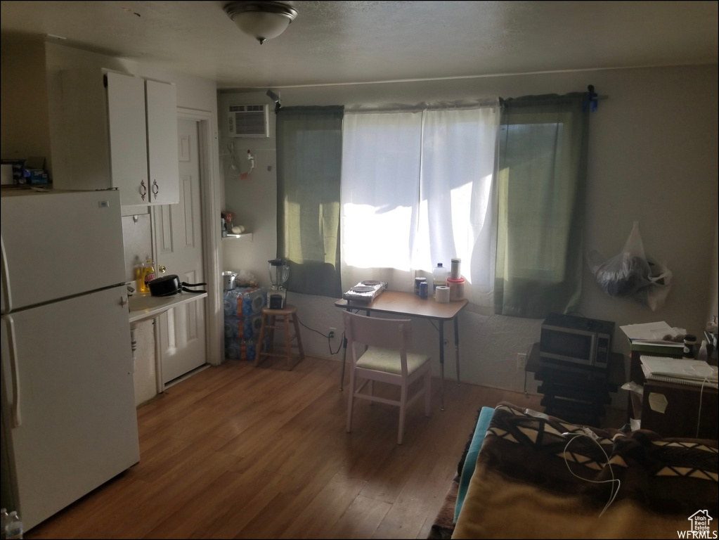 Dining room with wood finished floors, an AC wall unit, and a desk