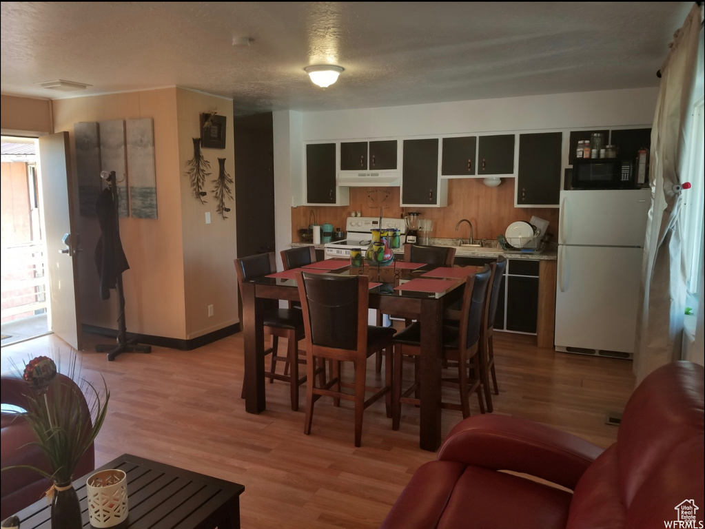 Dining room with light wood-style flooring, a textured ceiling, and baseboards