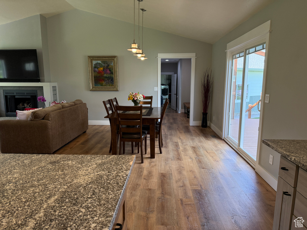 Dining area with lofted ceiling, wood finished floors, baseboards, and a fireplace