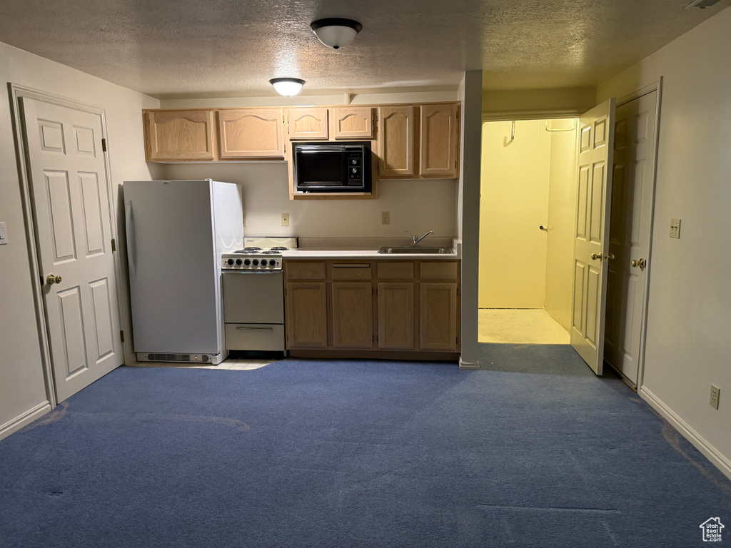 Kitchen featuring freestanding refrigerator, black microwave, stove, a sink, and a textured ceiling