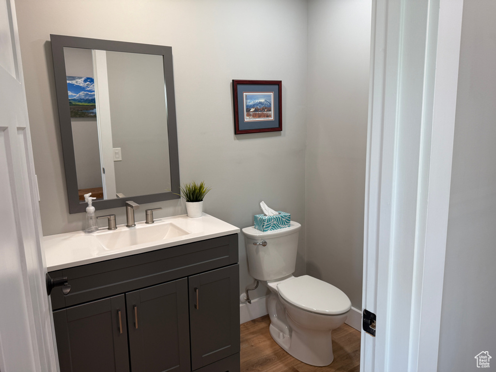 Bathroom featuring toilet, vanity, wood finished floors, and baseboards