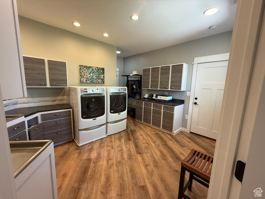 Laundry area with washer and dryer, light wood-type flooring, and recessed lighting